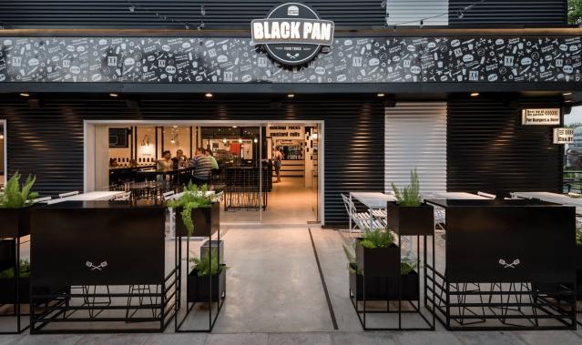 Vista nocturna de la sucursal 3 con iluminación cálida y clientes disfrutando